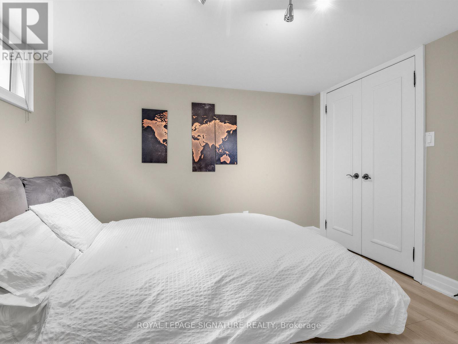 A bedroom with a white bed and two framed pictures on the wall.