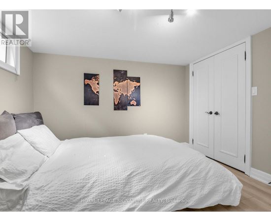 A bedroom with a white bed and two framed pictures on the wall.