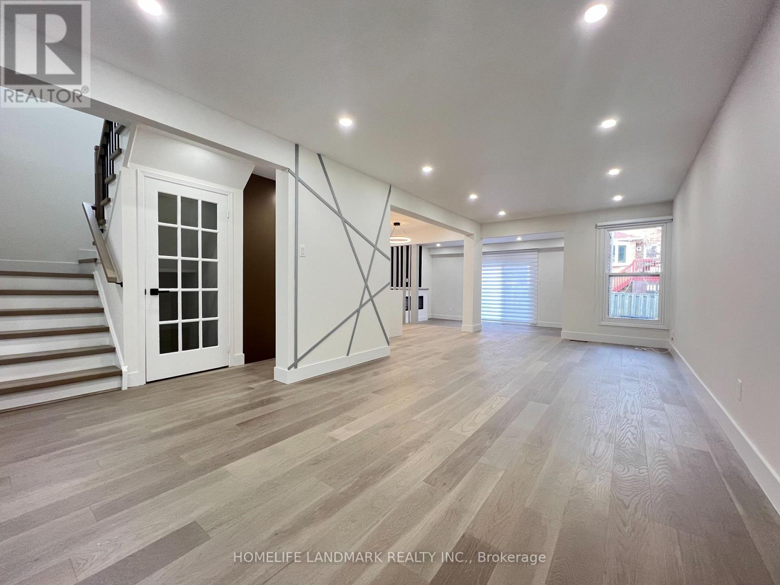 A spacious room with wooden flooring and white walls.
