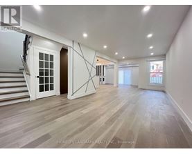 A spacious room with wooden flooring and white walls.