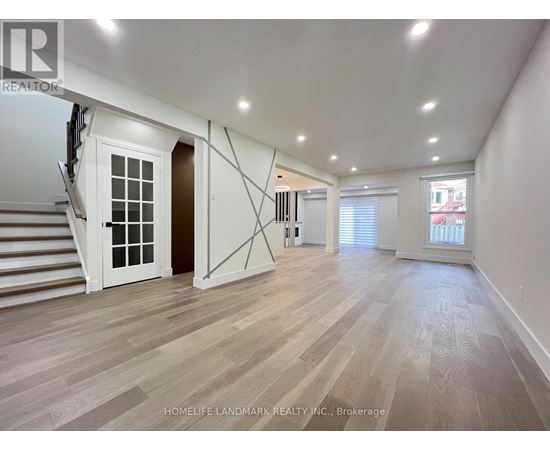 A spacious room with wooden flooring and white walls.