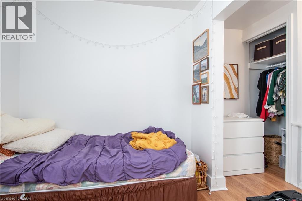 A bedroom with a bed covered in a purple blanket and a white dresser with a basket on top.