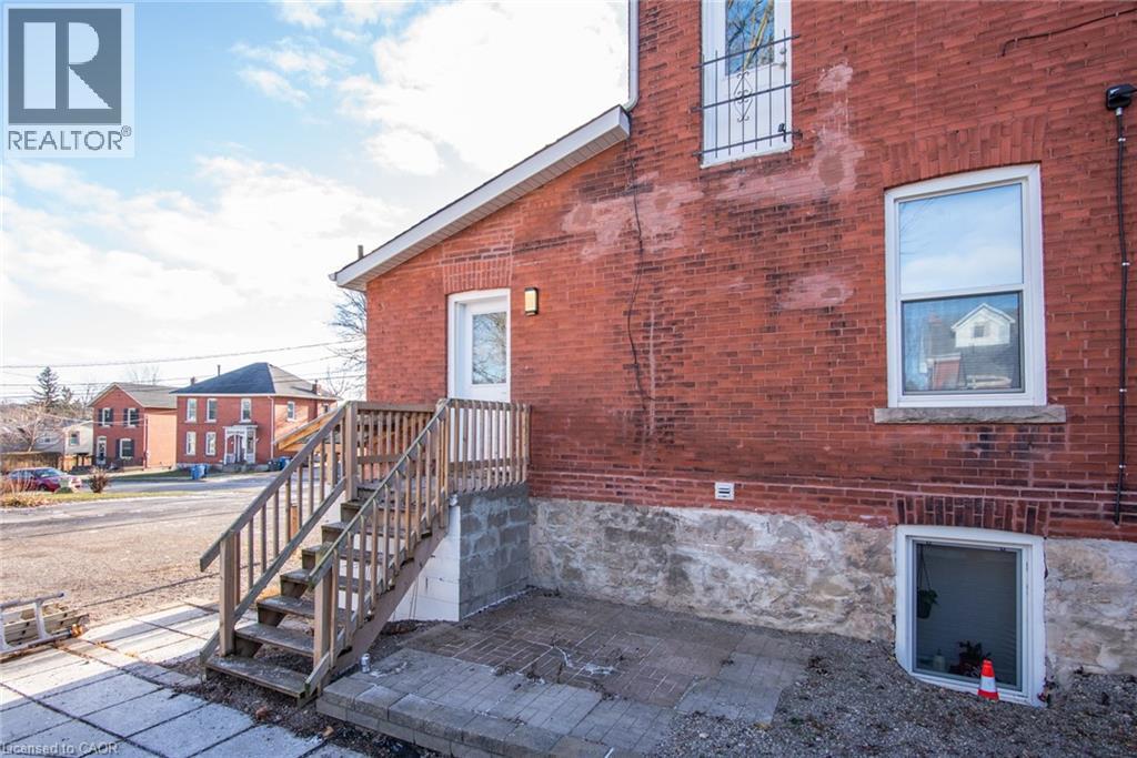 A red brick house with a wooden staircase leading to a basement entrance.