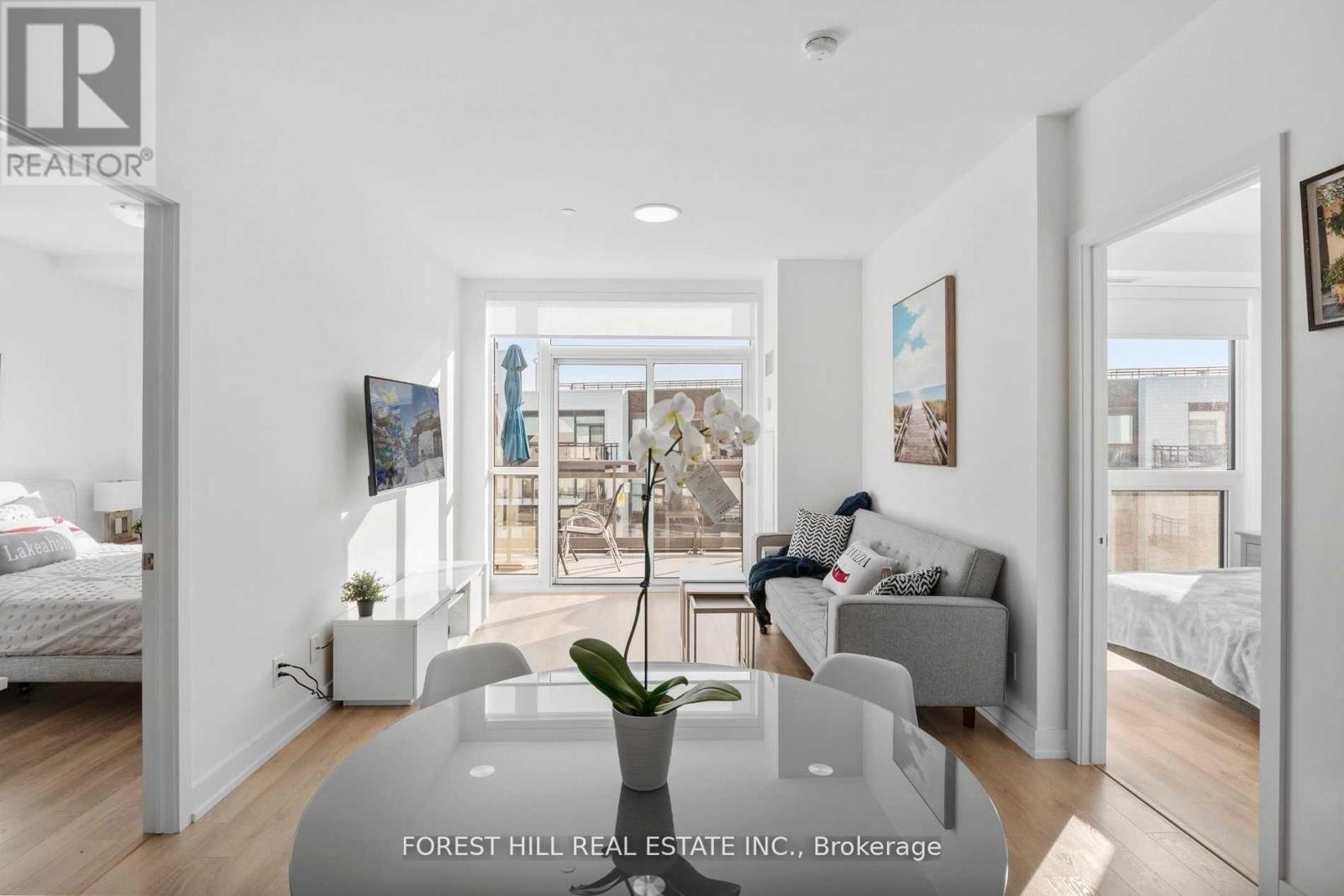 A real estate listing image of a modern bedroom with a glass table and two beds.