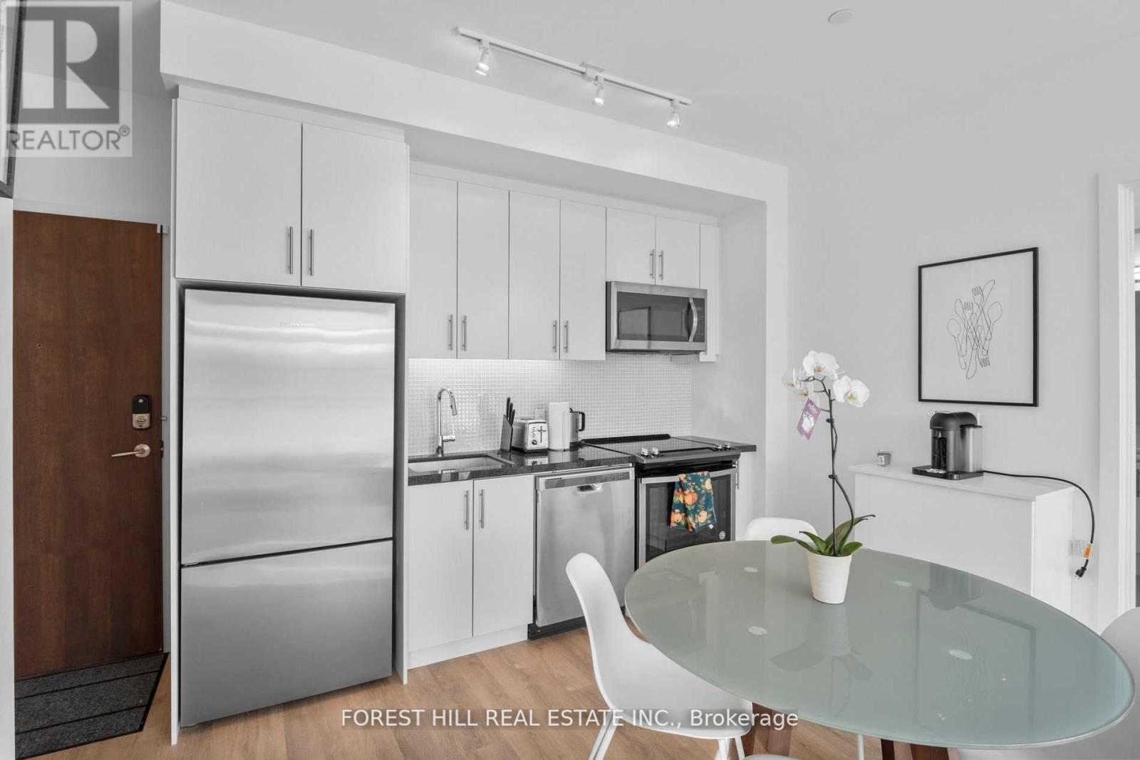 A modern kitchen with a glass table and white chairs.