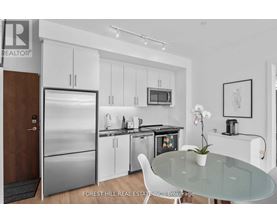 A modern kitchen with a glass table and white chairs.