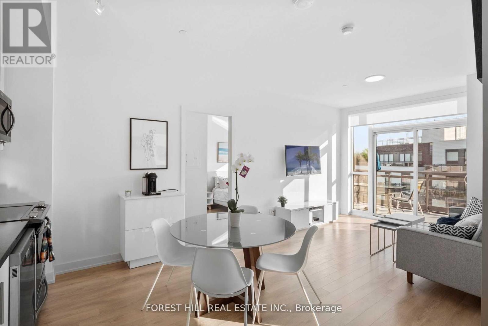 A modern dining room with a glass table and white chairs.