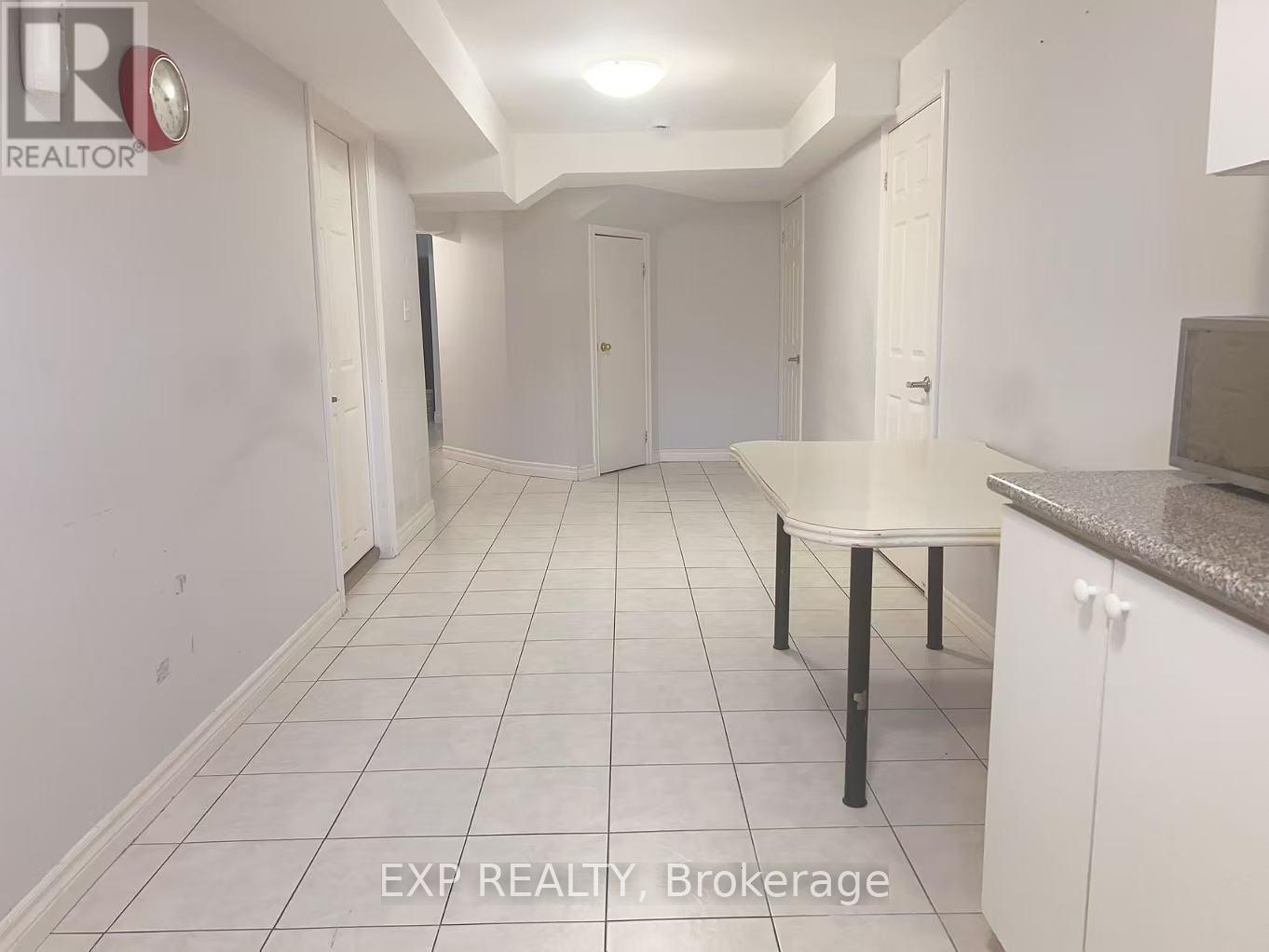 A white tiled hallway with a table and chairs in the foreground.