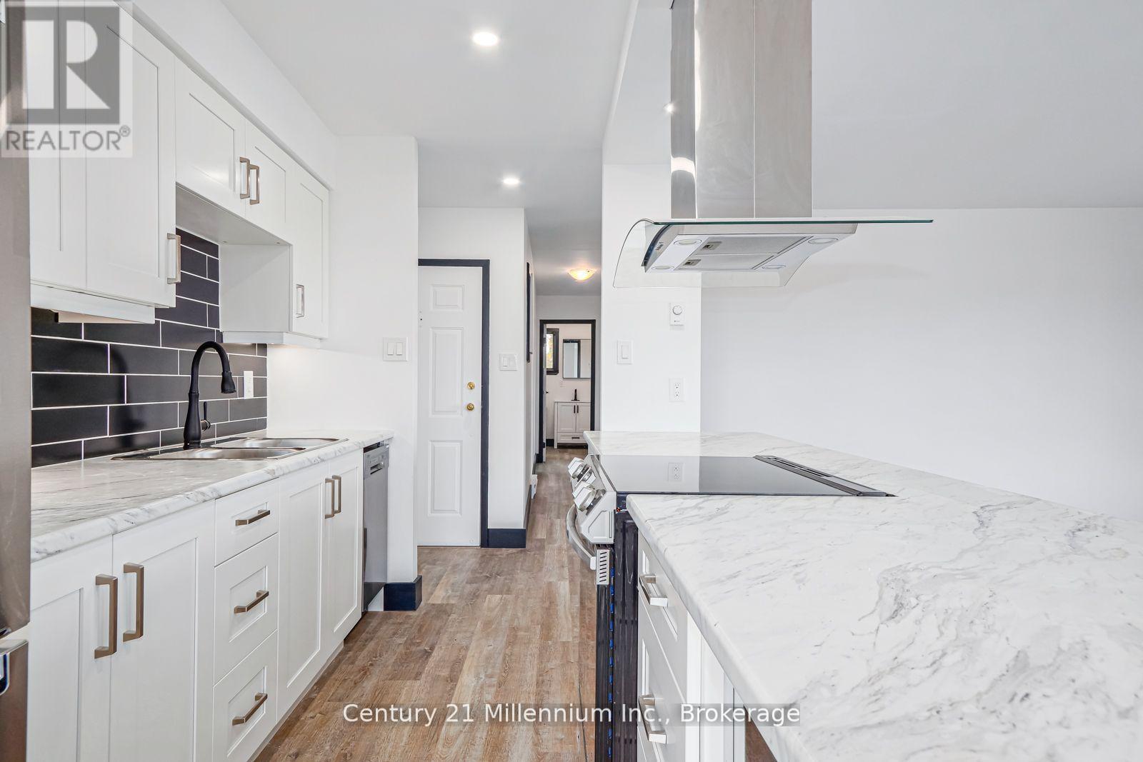 A modern kitchen with white cabinets and a marble countertop.