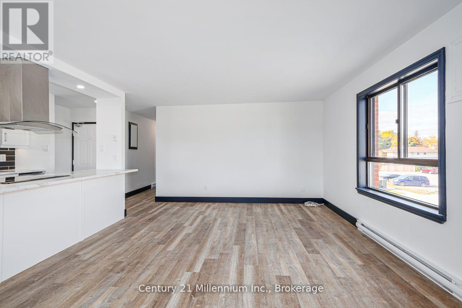 A spacious room with wooden flooring and white walls, ready for a Century 21 Millennium Inc. brokerage listing.