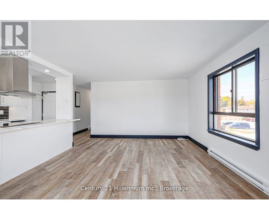 A spacious room with wooden flooring and white walls, ready for a Century 21 Millennium Inc. brokerage listing.