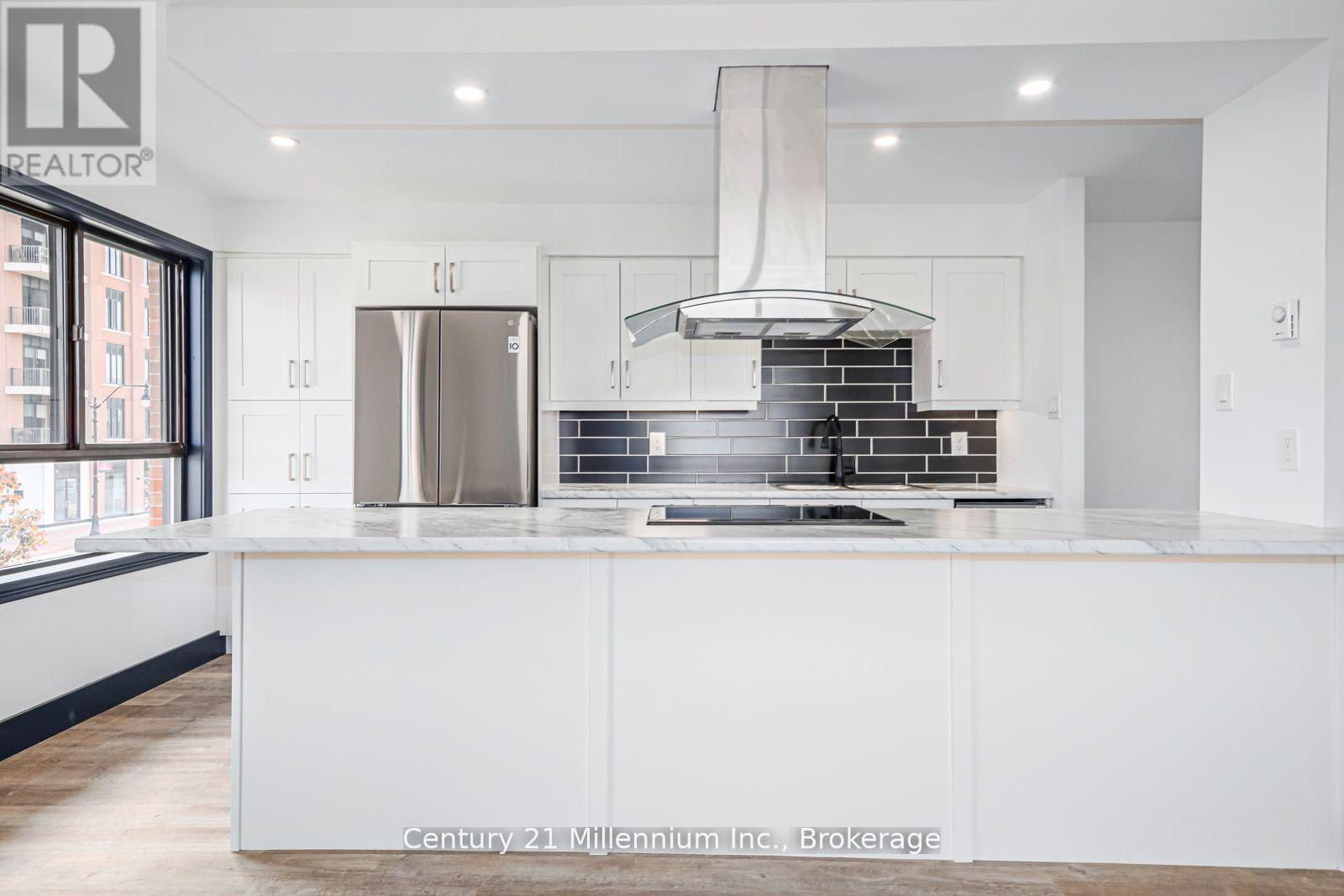 A modern kitchen with white cabinets and a stainless steel refrigerator.