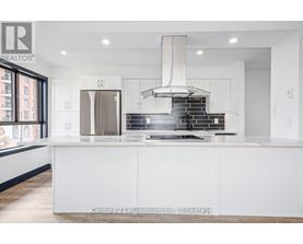 A modern kitchen with white cabinets and a stainless steel refrigerator.