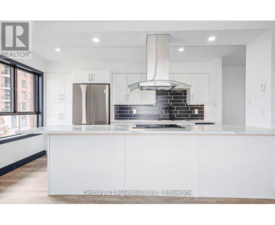 A modern kitchen with white cabinets and a stainless steel refrigerator.