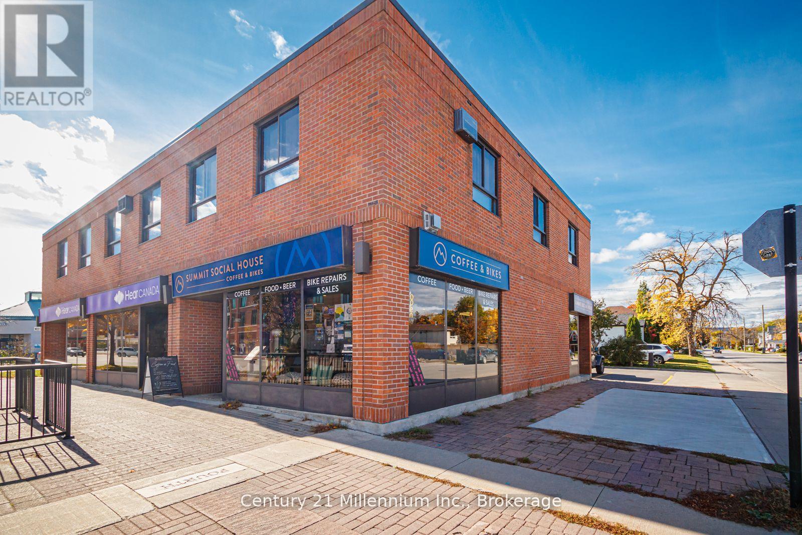 A brick building with a blue sign that says "Century 21 Millennium Inc. Brokerage".