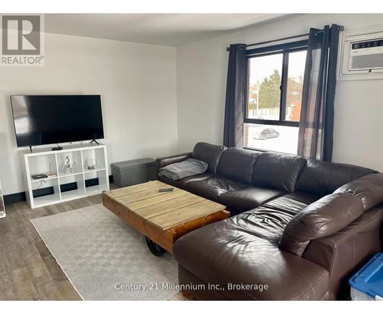 A living room with a brown leather couch and a flat screen TV.