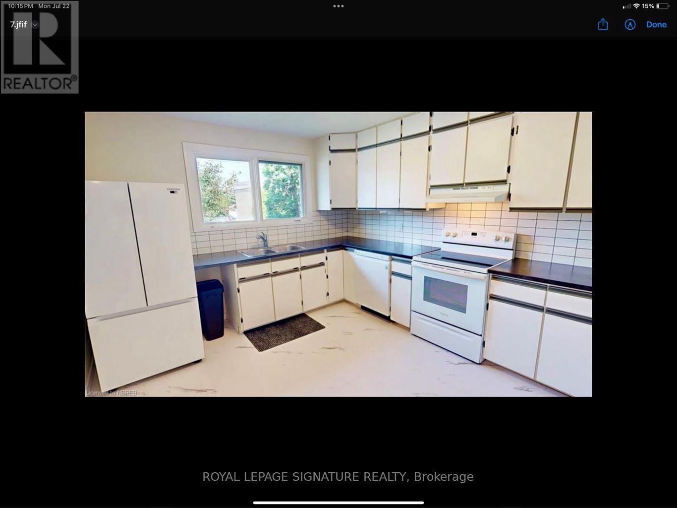 A kitchen with white cabinets and a blue trash bin.