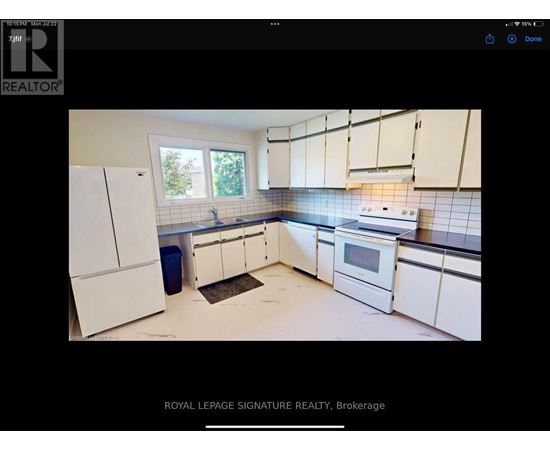 A kitchen with white cabinets and a blue trash bin.