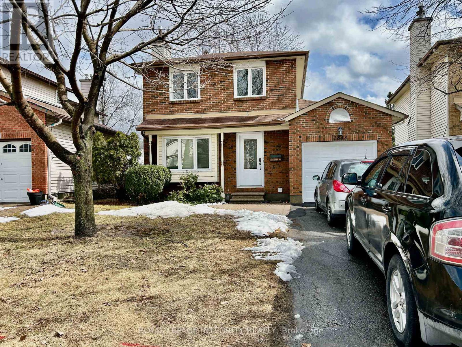 A house with a tree in front and cars parked in the driveway.