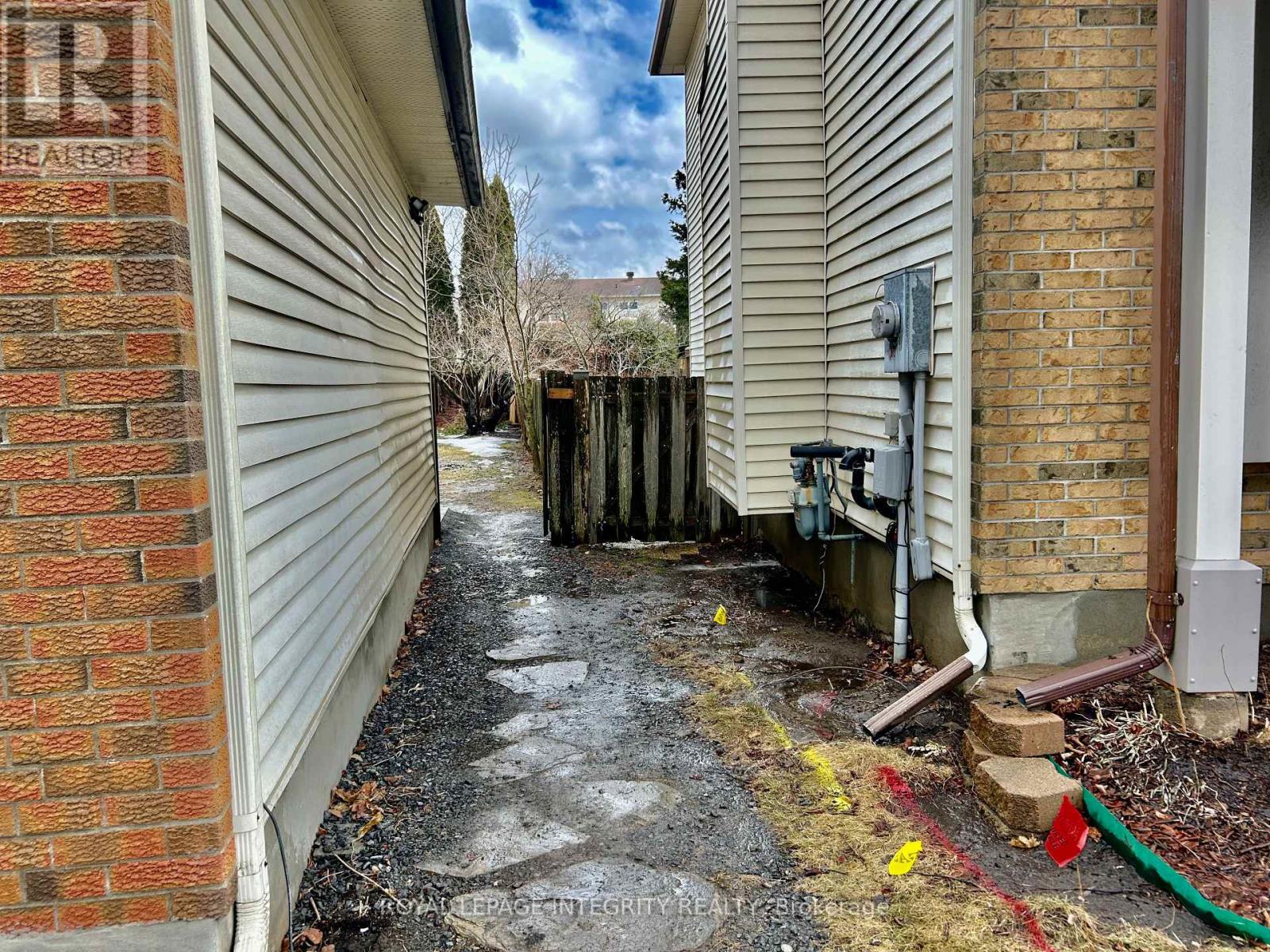 A narrow alley between two buildings with a red hose on the right.