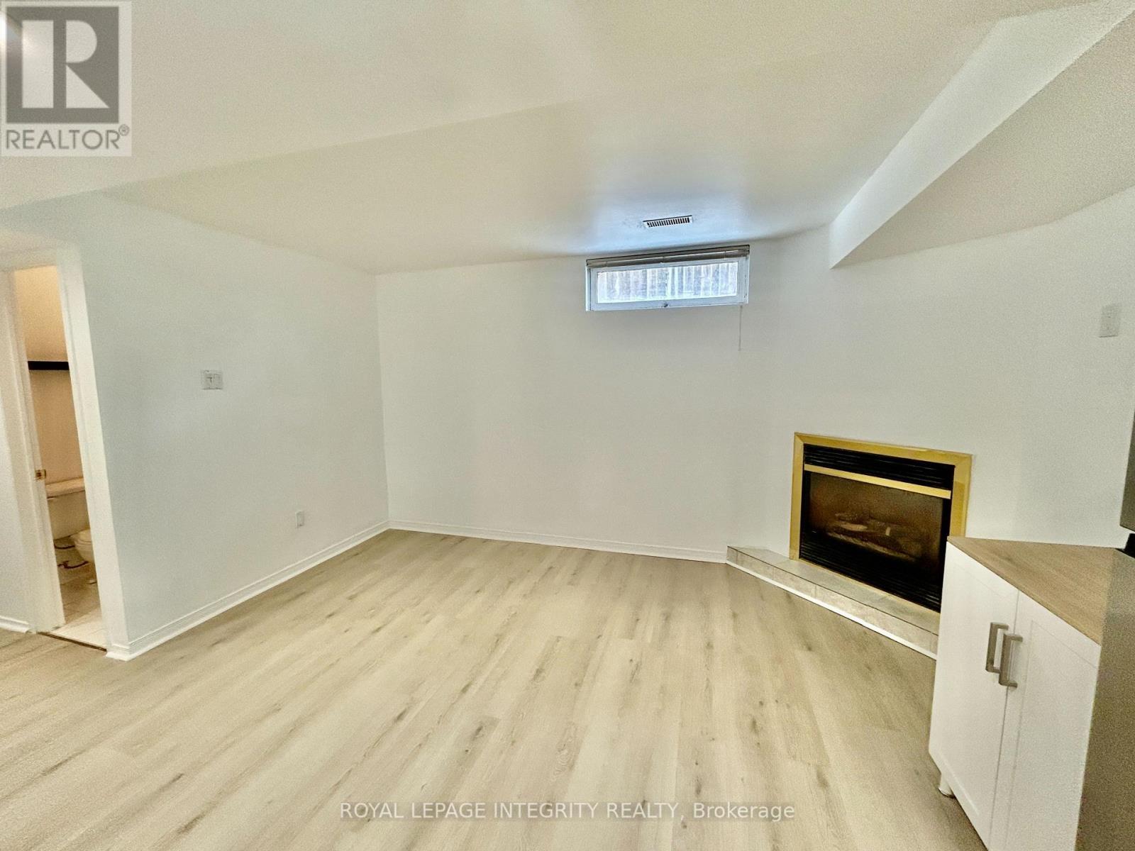 A spacious room with a fireplace and wooden flooring.