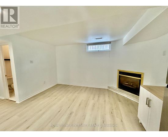 A spacious room with a fireplace and wooden flooring.