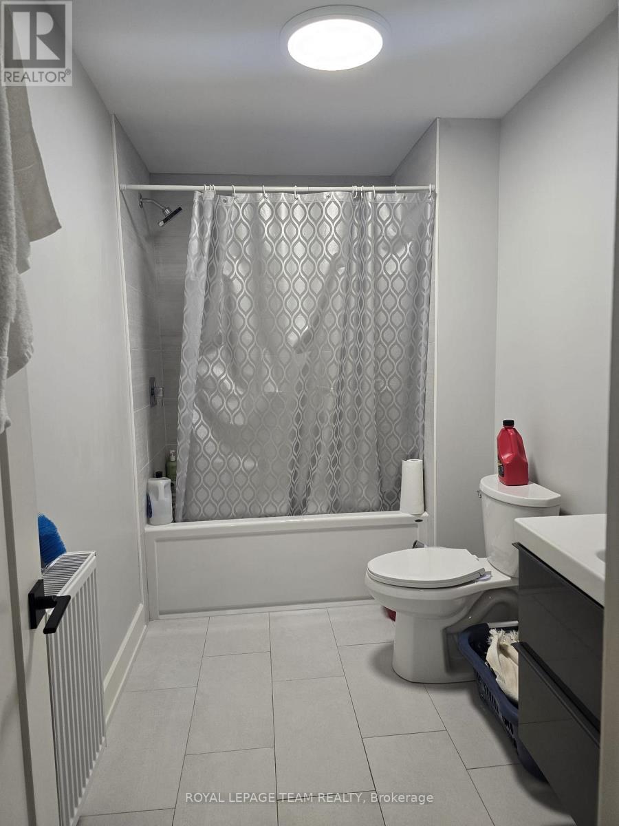 A white washing machine is in a small space with a blue bottle and a red bottle on the floor.