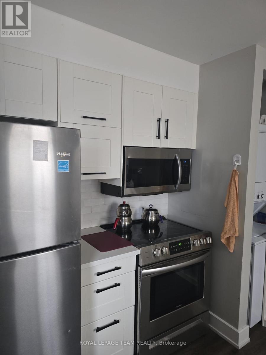 A kitchen with a stainless steel refrigerator, a microwave above the stove, and white cabinets.