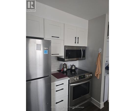A kitchen with a stainless steel refrigerator, a microwave above the stove, and white cabinets.