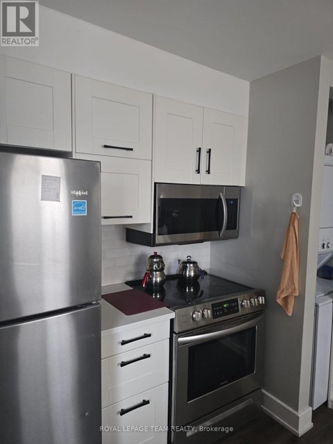A kitchen with a stainless steel refrigerator, a microwave above the stove, and white cabinets.