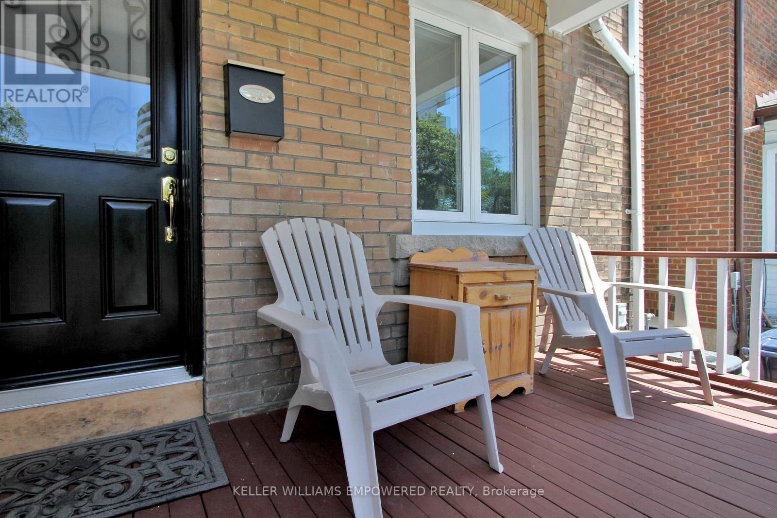 Two white chairs are on a porch.
