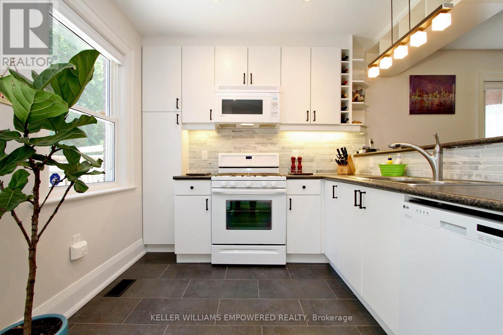 A white kitchen with a stove top oven and a microwave above it.