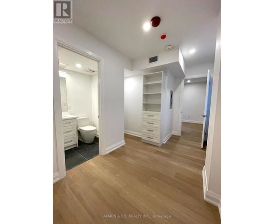 A spacious room with wood flooring and white walls.