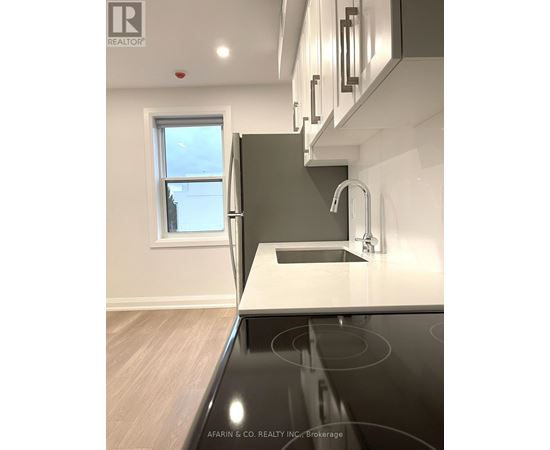 A modern kitchen with a stainless steel stove top and a window.
