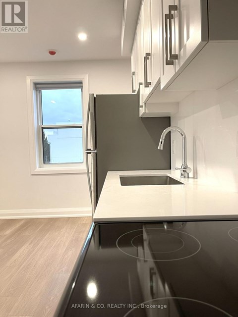 A modern kitchen with a stainless steel stove top and a window.