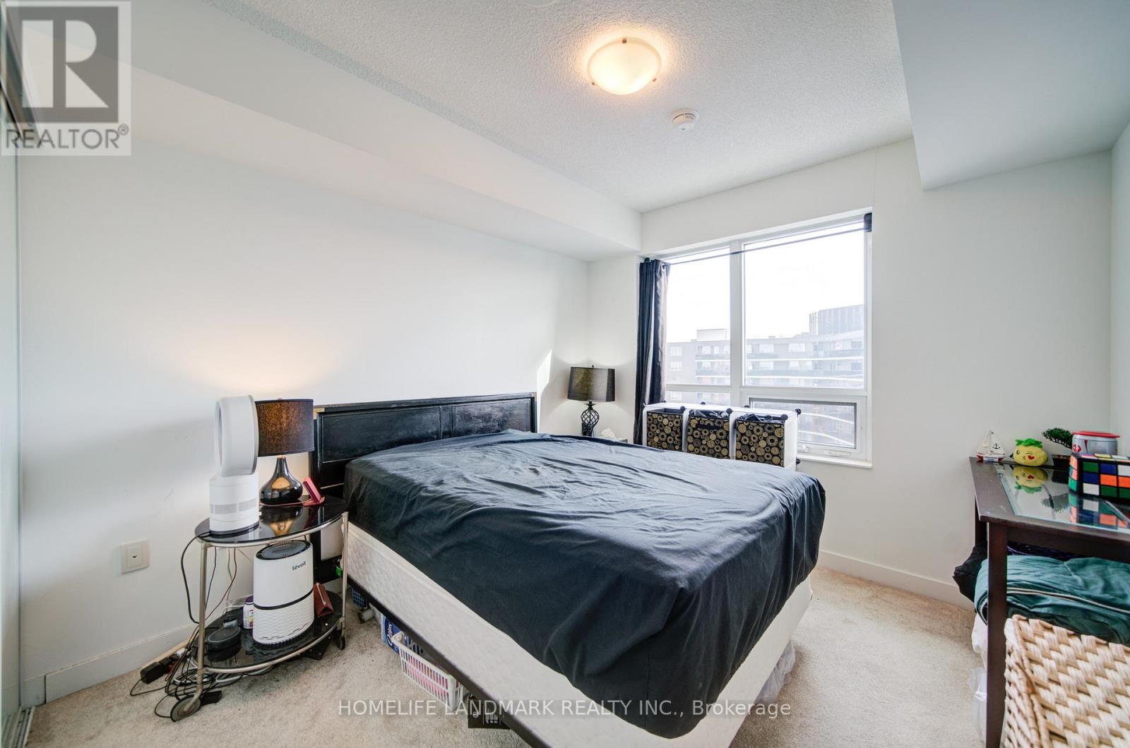 A bedroom with a bed, nightstand, and window.