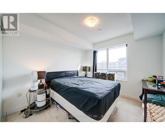 A bedroom with a bed, nightstand, and window.