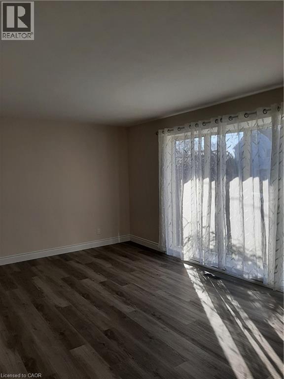 A room with wooden flooring and a window with white curtains.