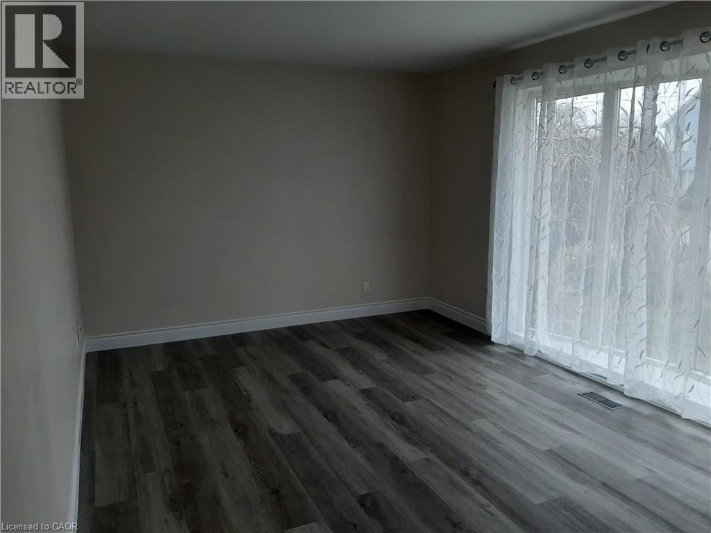 A room with wooden flooring and a window with curtains.