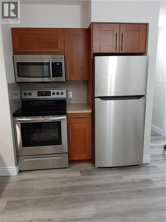A kitchen with a stainless steel refrigerator and an oven with a microwave above it.