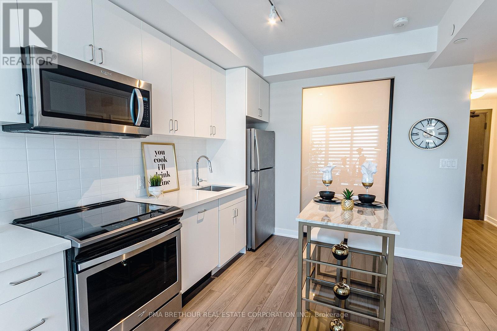 A modern kitchen with stainless steel appliances and a wooden floor.