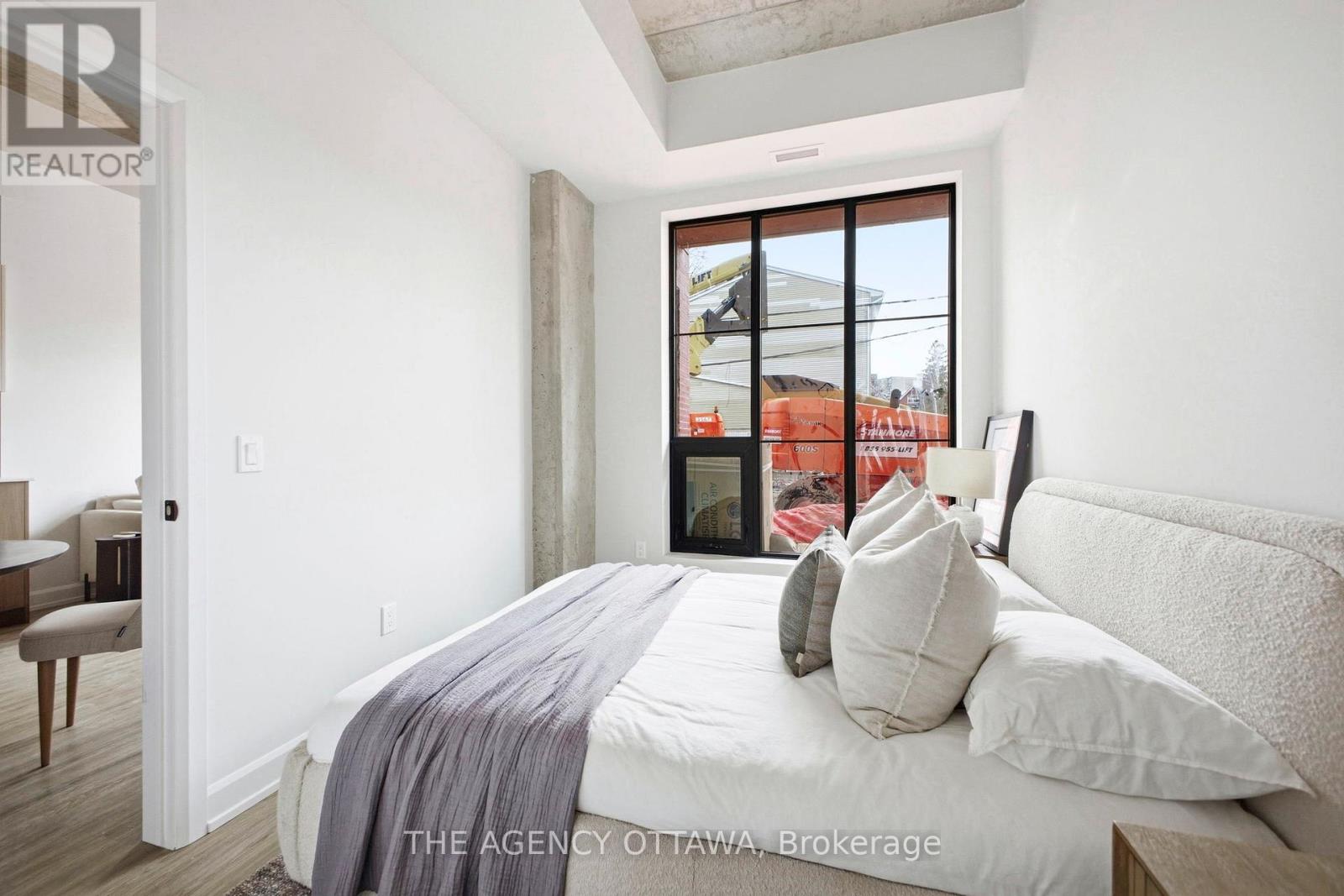 A bedroom with a large bed and a window overlooking a construction site.