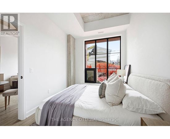 A bedroom with a large bed and a window overlooking a construction site.