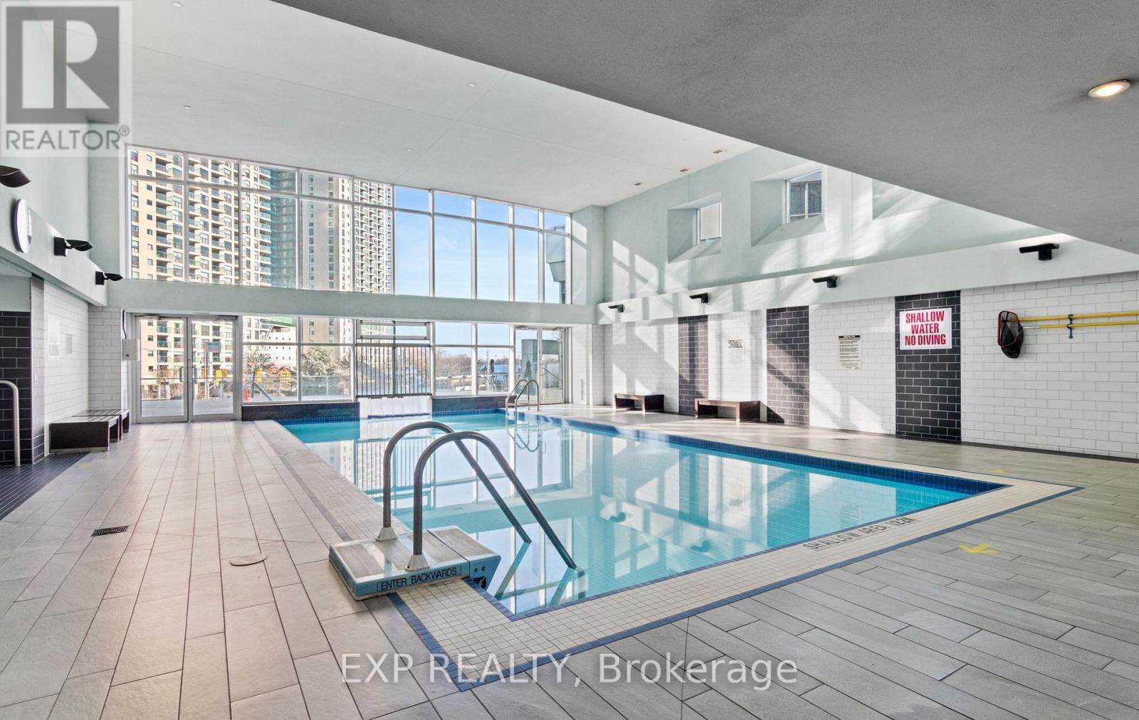 A large indoor swimming pool with a diving board.