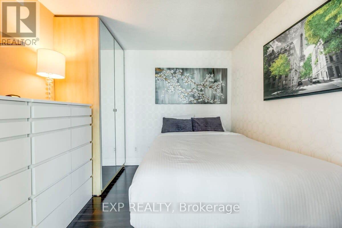 A bedroom with a bed, a lamp, and a painting on the wall.