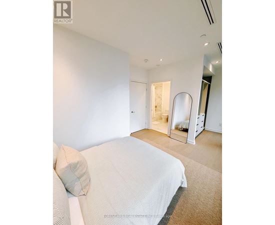 A bedroom with a large bed and a mirrored closet door.