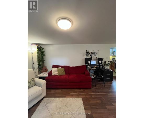A red couch sits in a living room with a white couch to its left.