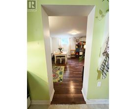 A hallway with a green wall and a white doorway leading to a dining room.
