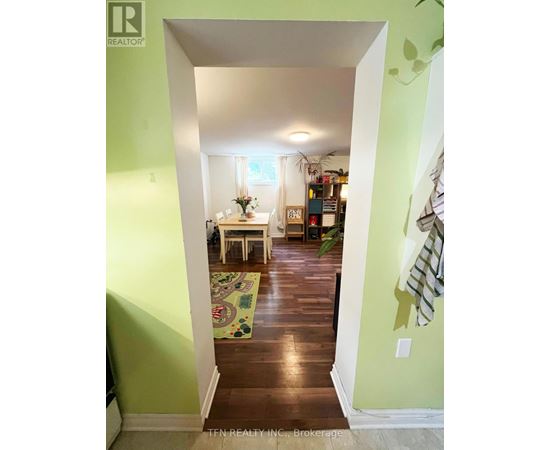 A hallway with a green wall and a white doorway leading to a dining room.