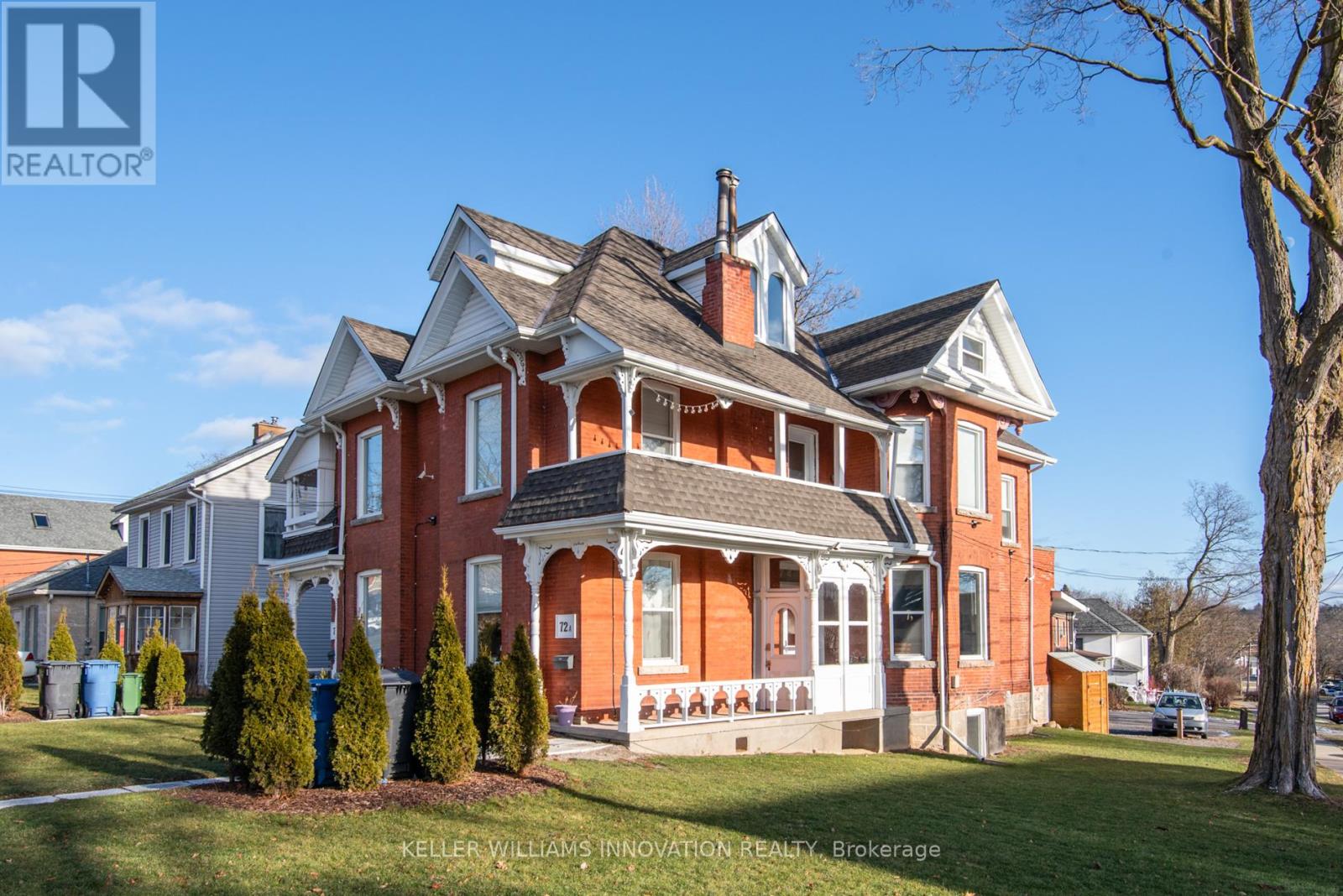 A large red brick house with a white trim and a balcony on the second floor.